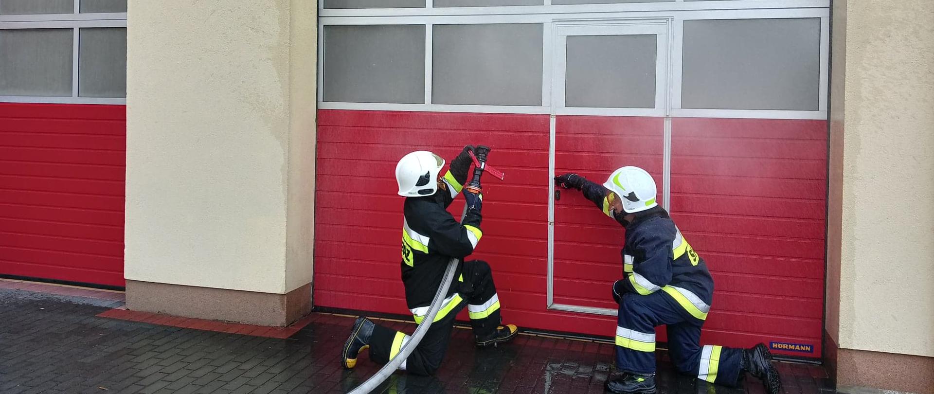 Zdjęcie przedstawia dwóch strażaków podczas ćwiczenia wejścia do pomieszczenia, w którym rozwija się pożar.