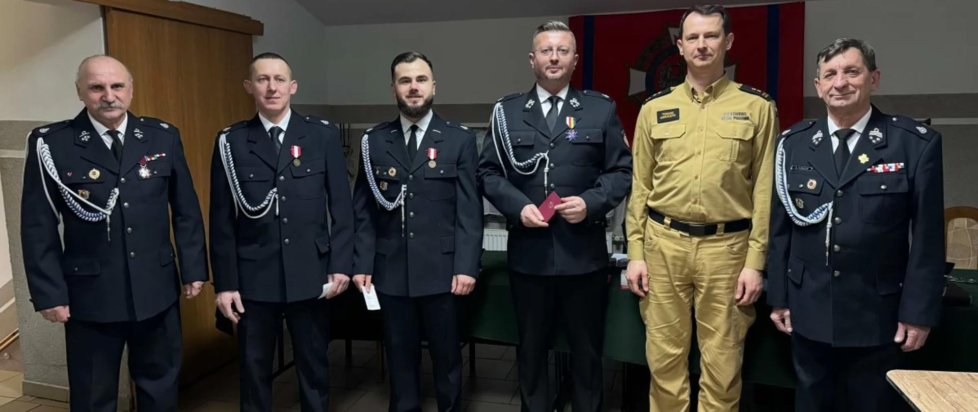 Zdjęcie przedstawia zastępcę Komendanta Powiatowego PSP w Zambrowie
w ubraniu służbowym oraz członków OSP w Kołakach Kościelnych pozujących do zdjęcia.