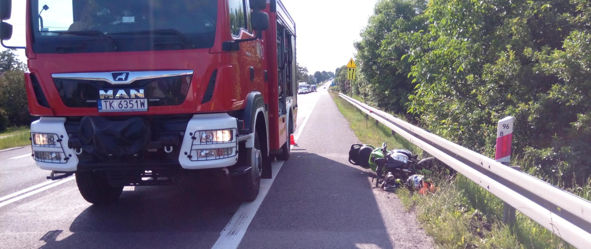 Na drodze zapakowany jest samochód straży pożarnej, obok leży motocykl.