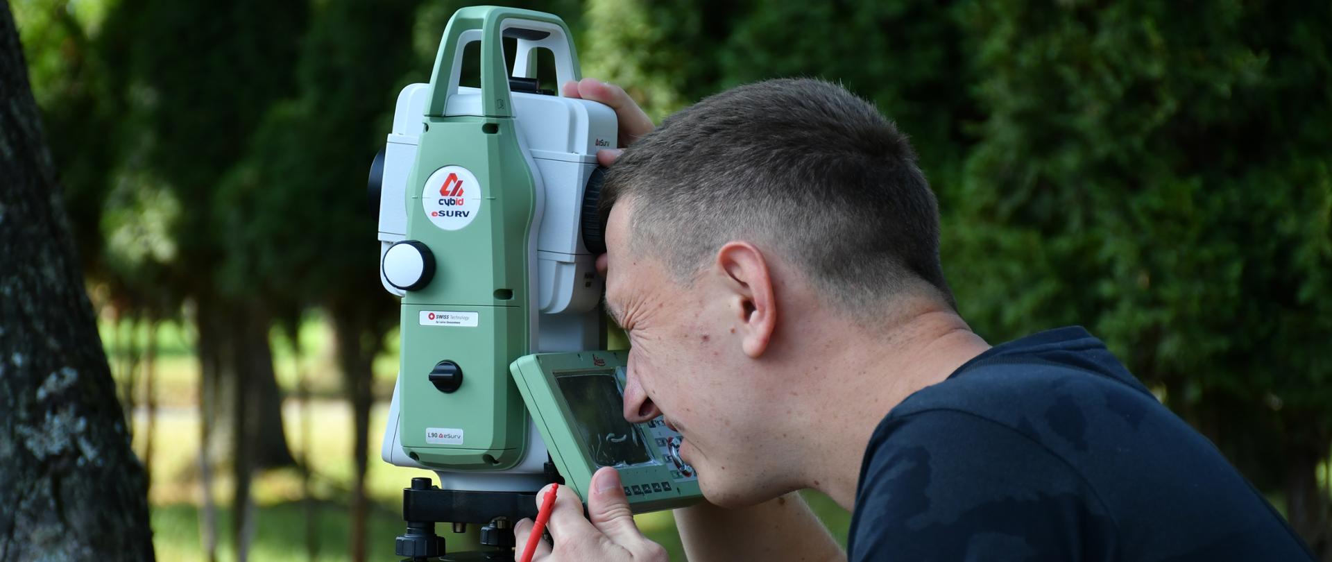 Mężczyzna obsługuje tachimetr ma otwartym powietrzu