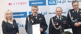 Zdjęcie przedstawia zarząd jednostki OSP Piecnik trzymająca dyplom i okolicznościowy grawer w towarzystwie organizatorów konkursu