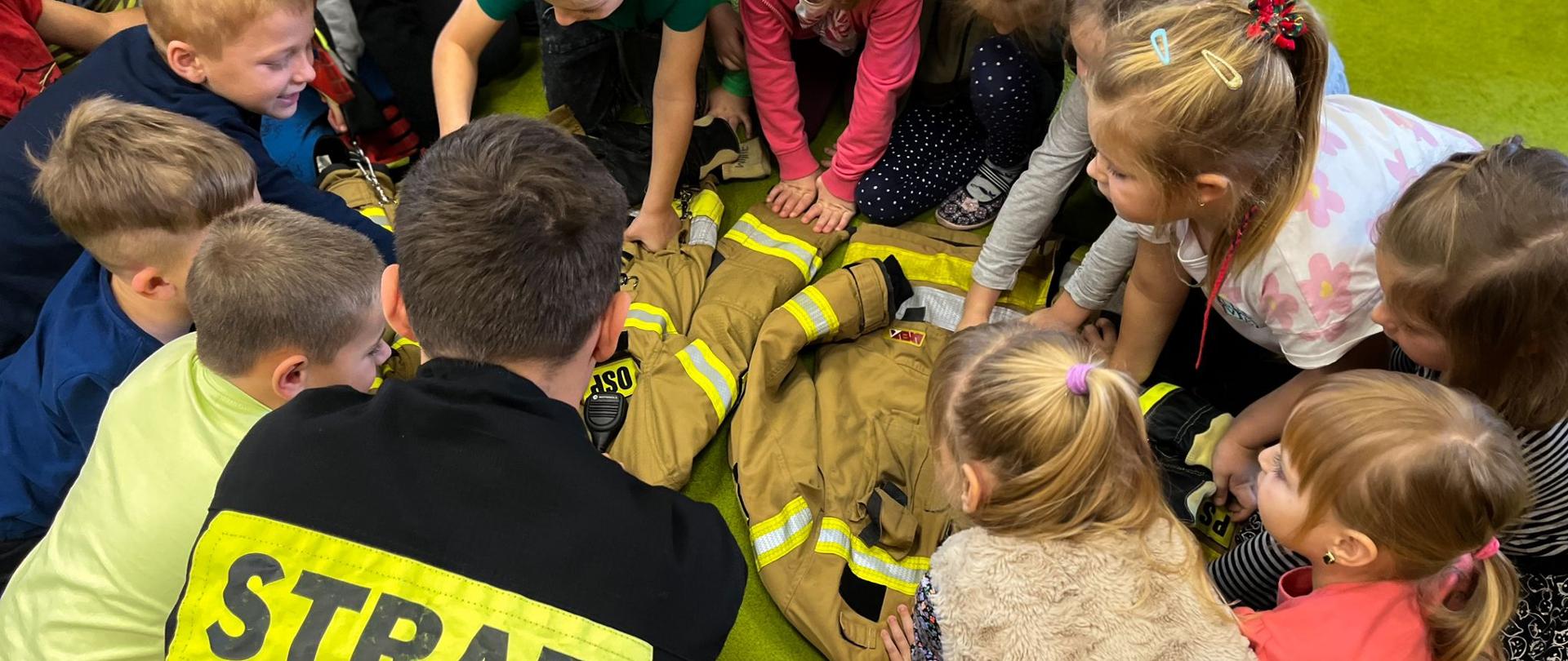Strażak prezentuje ubranie specjalne przedszkolakom.