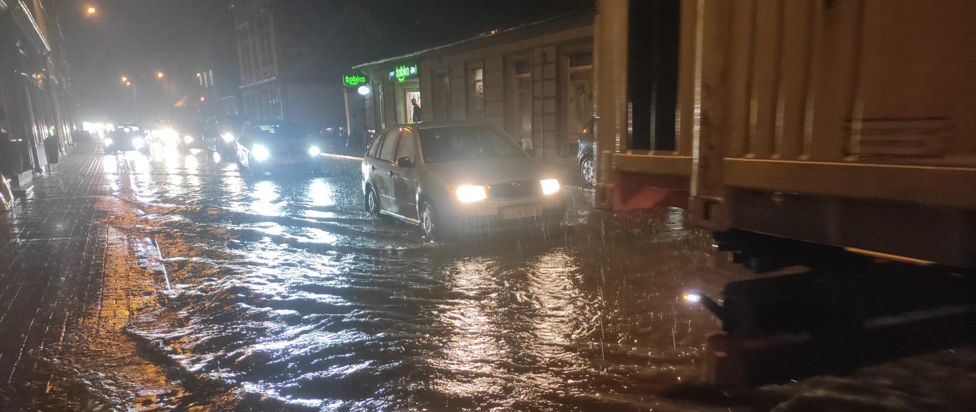 Zalana ul. Św. Ducha w Strzelnie. Drogą przejeżdżają samochody
