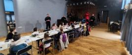 Dzieci słuchają prelekcji strażaków na temat bezpieczeństwa podczas ferii zimowych