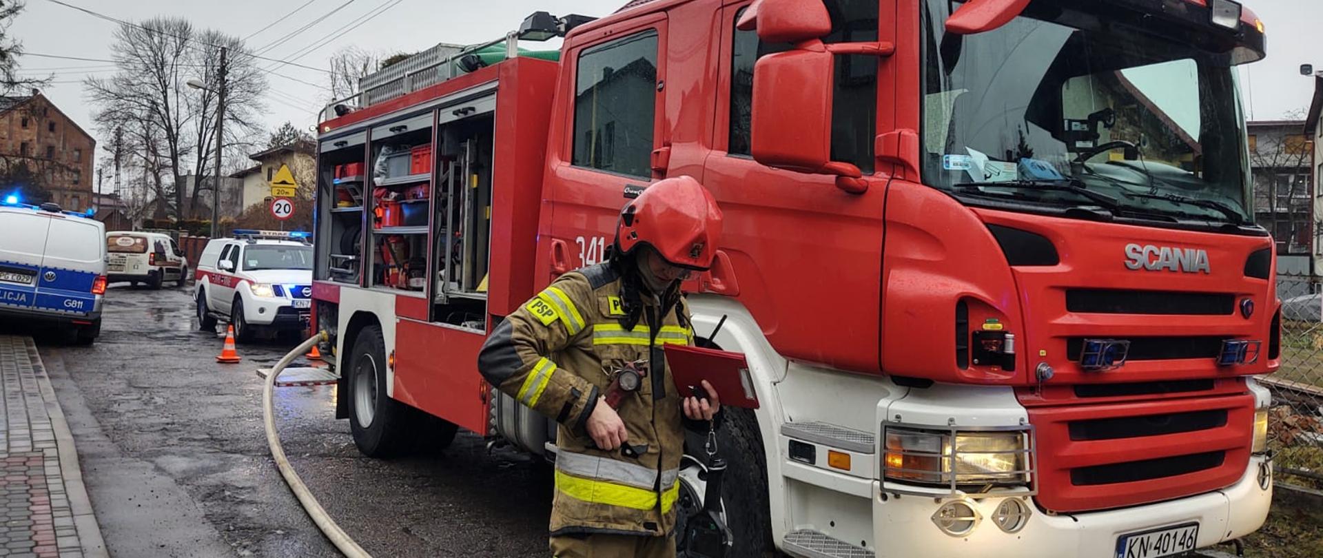 Samochód pożarniczy oraz strażak biorący udział w działaniach ratowniczych.