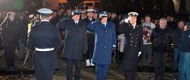 Funkcjonariusze służb mundurowych oddają honor po złożeniu wieńca pod pomnikiem.