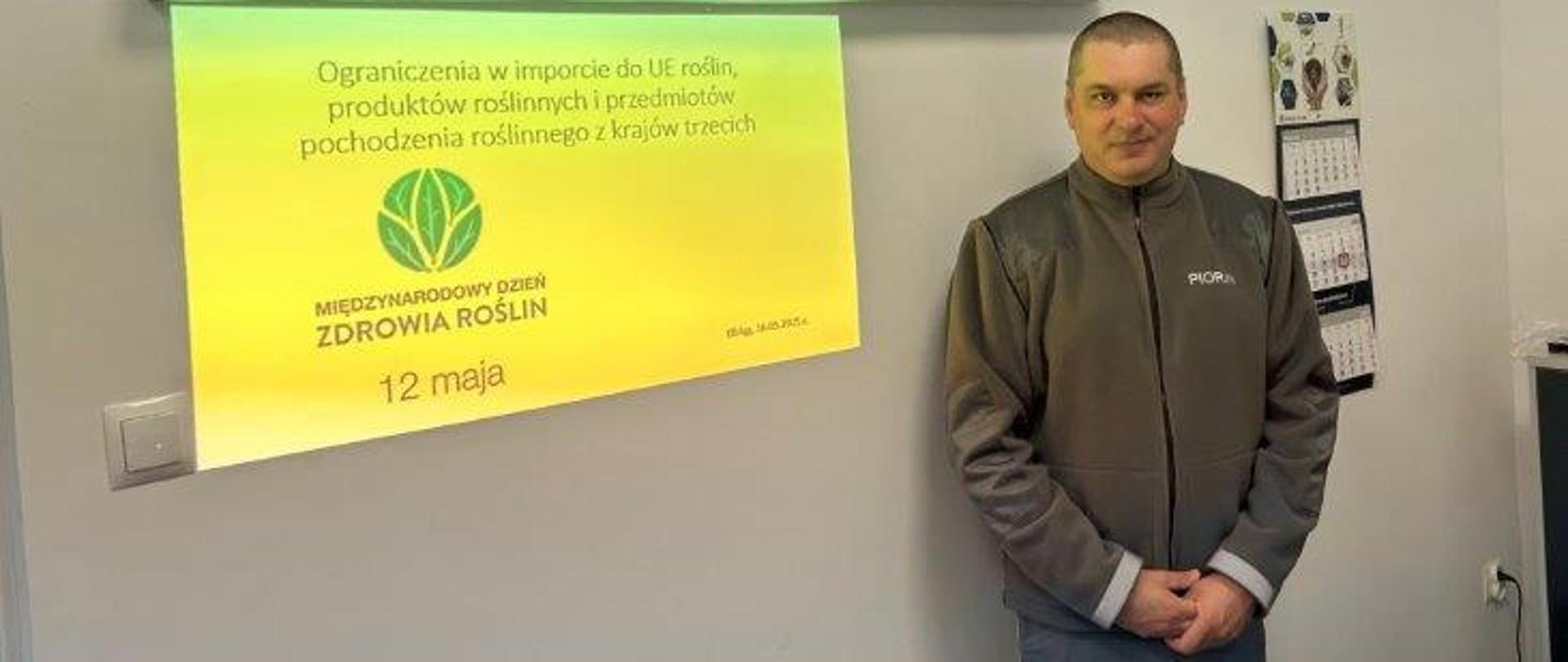 mężczyzna ubrany w mundur PIORiN. W tle widać prezentację informującą o ograniczeniach w imporcie do UE roślin, produktów roślinnych i przedmiotów pochodzenia roślinnego z krajów trzecich