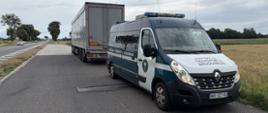 Na pierwszym planie (od prawej): przód i prawy bok oznakowanego furgonu mazowieckiej Inspekcji Transportu Drogowego. W tle: za radiowozem Inspekcji Transportu Drogowego stoi zatrzymany do kontroli ciągnik siodłowy z podpiętą naczepą. Obok, po jezdni drogi krajowej, przejeżdżają samochody osobowe i ciężarowe. 