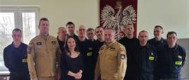 Na zdjęciu Komendant Miejski Państwowej Straży Pożarnej w Częstochowie wraz z Dowódcą Jednostki Ratowniczo – Gaśniczej numer 1 w Częstochowie, Panią Martą oraz strażakami Jednostki Ratowniczo – Gaśniczej numer 1 w Częstochowie. W tle Godło Państwowe.