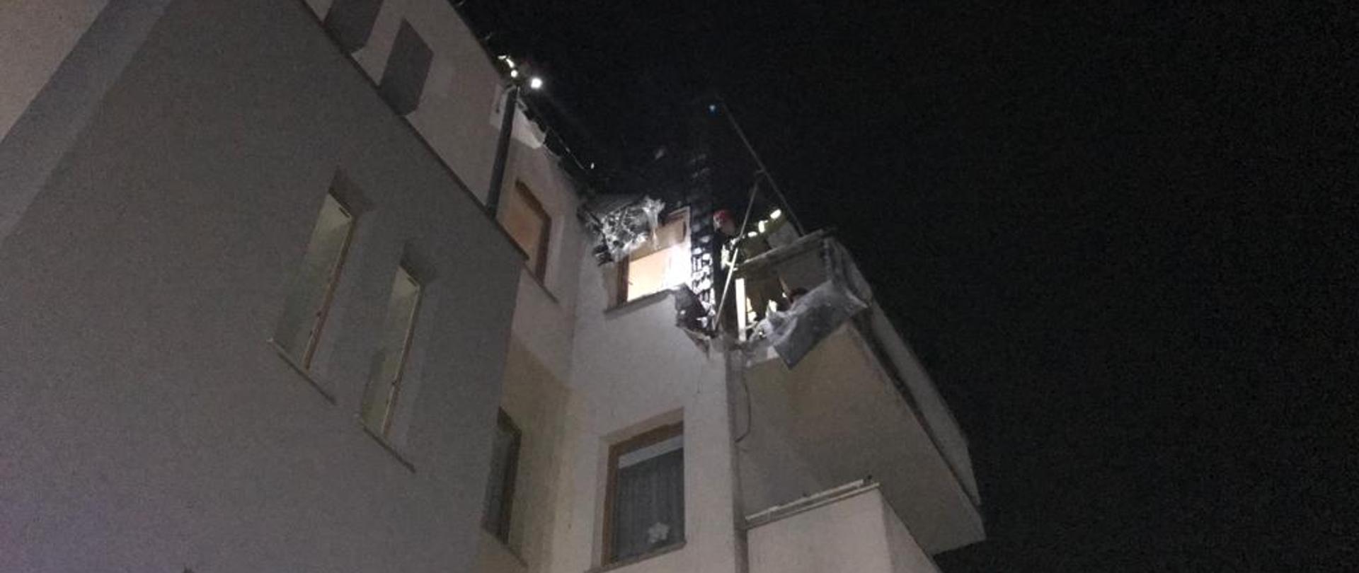 Na zdjęciu widać budynek wielorodzinny oraz spaloną elewację zewnętrzną przy balkonie mieszkania znajdującego się na ostatnim piętrze. Jest pora nocna