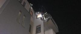 Na zdjęciu widać budynek wielorodzinny oraz spaloną elewację zewnętrzną przy balkonie mieszkania znajdującego się na ostatnim piętrze. Jest pora nocna
