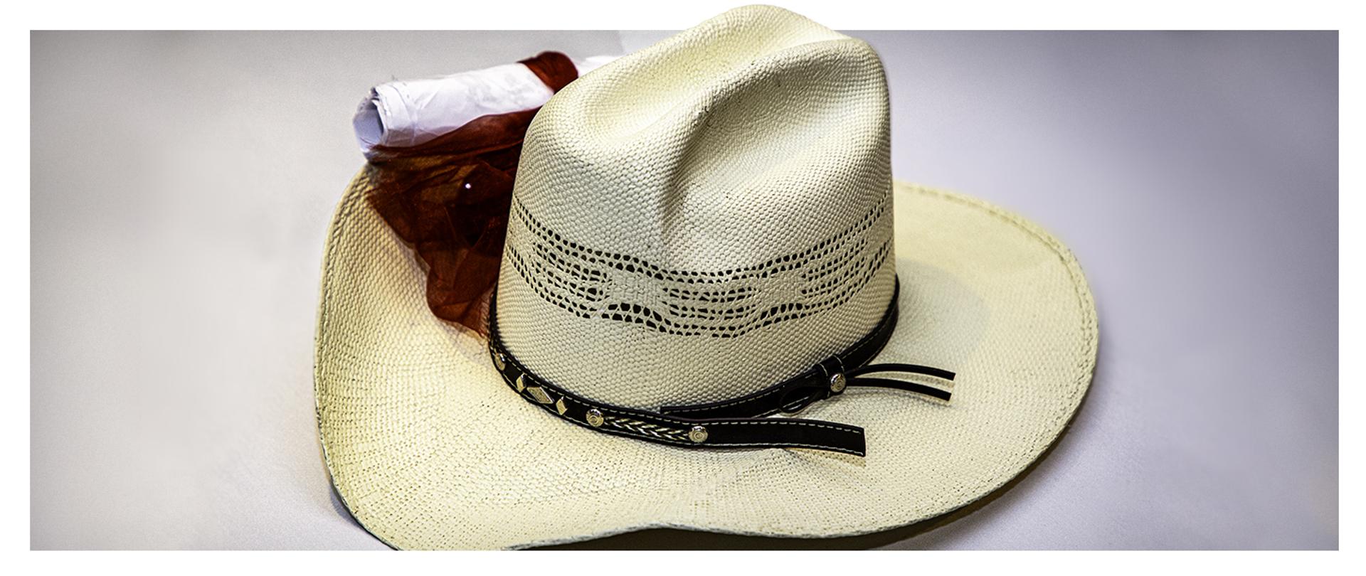 Kowbojski kapelusz i zwinięty papier w tle