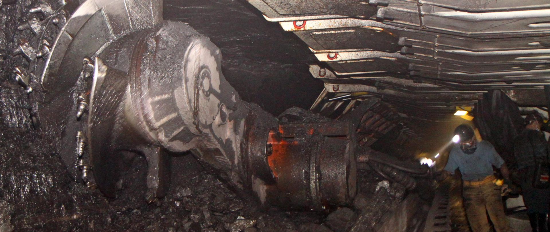 Górnicy w kopalni. Węgiel, maszyna, mężczyźni w kaskach