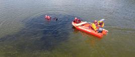 Strażacy łodzią ratowniczą podpływają do poszkodowanego