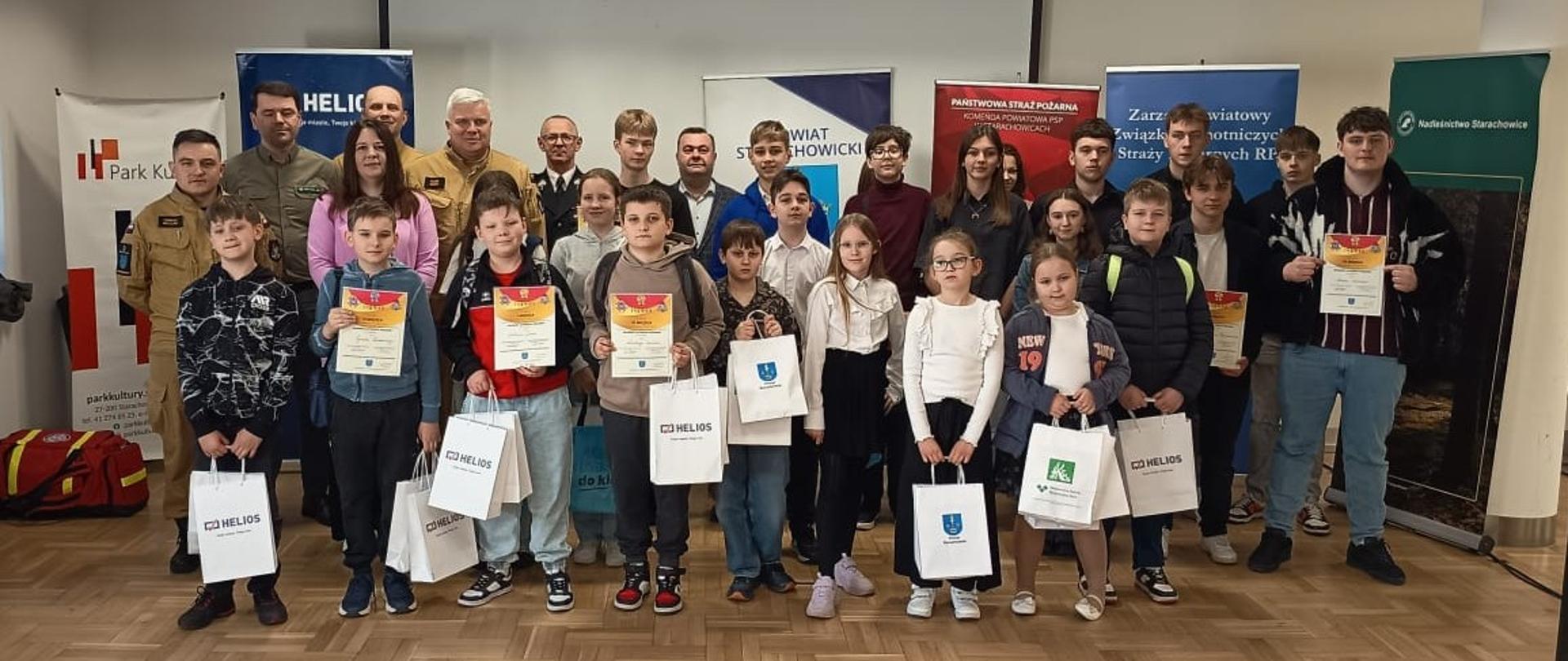 Uczestnicy turnieju z dyplomami i nagrodami, w tle banery sponsorów