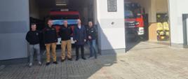 Zdjęcie przedstawia cztery osoby stojące przed siedzibą OSp Miłosław