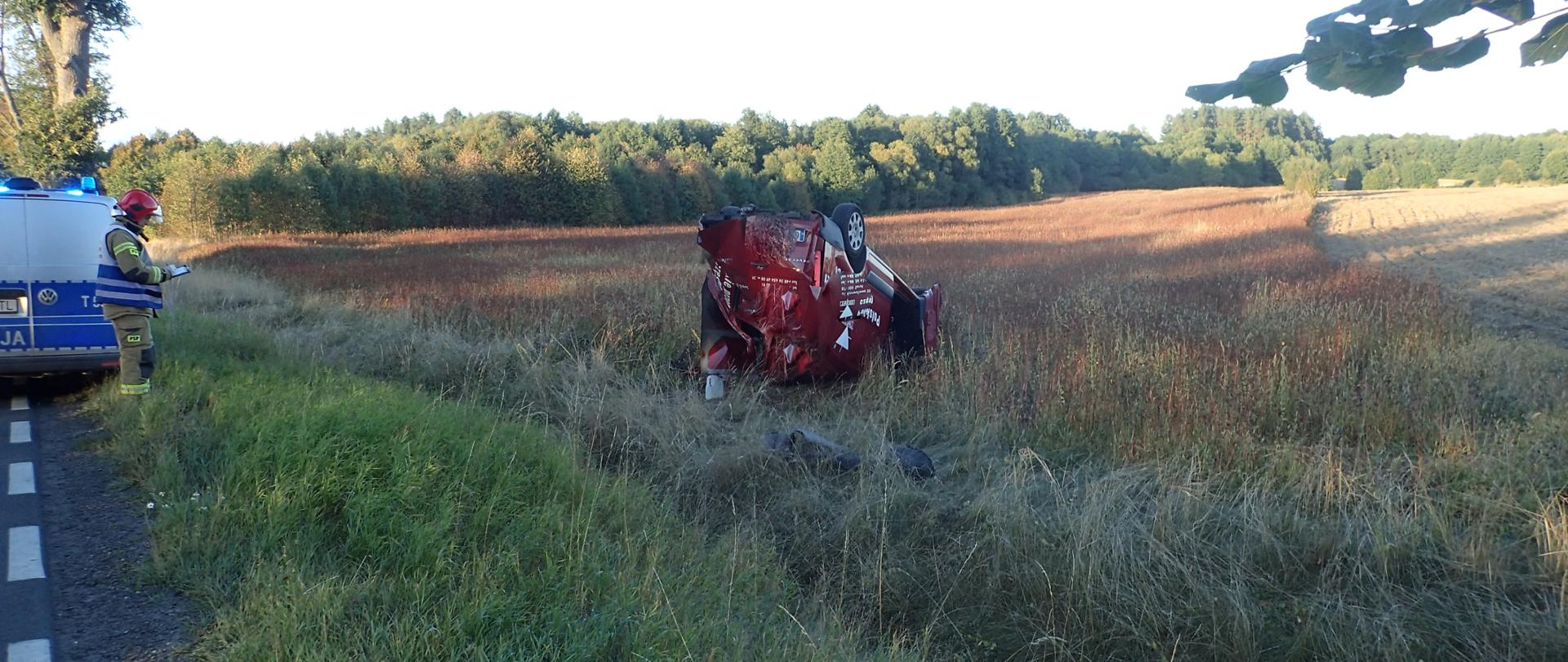 Zdjęcie przedstawia samochód osobowy znajdujący się na dachu w przyrożnym rowie.