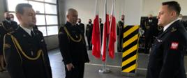 Na zdjęciu od lewej, widać stojących obok siebie dwóch oficerów: zdającego i przejmującego obowiązki Komendanta Powiatowego. Po prawej Opolski Komendant Wojewódzki PSP odbierający meldunki. W tle uczestniczący w uroczystości Komendanci Powiatowi PSP i funkcjonariusze KP PSP w Krapkowicach. 