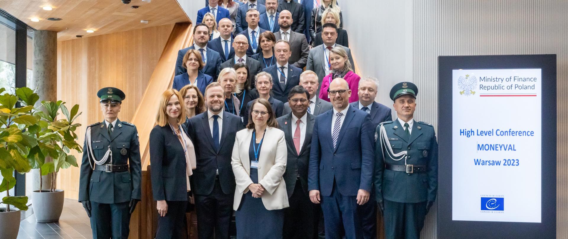 Uśmiechnięci uczestnicy spotkania Komitetu Moneyval w Warszawie w asyście funkcjonariuszy Służby Celno-Skarbowej. 