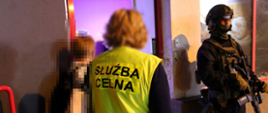 Funkcjonariusze przed wejściem do lokalu, na pierwszym planie osoba w kamizelce z napisem Służba Celna.