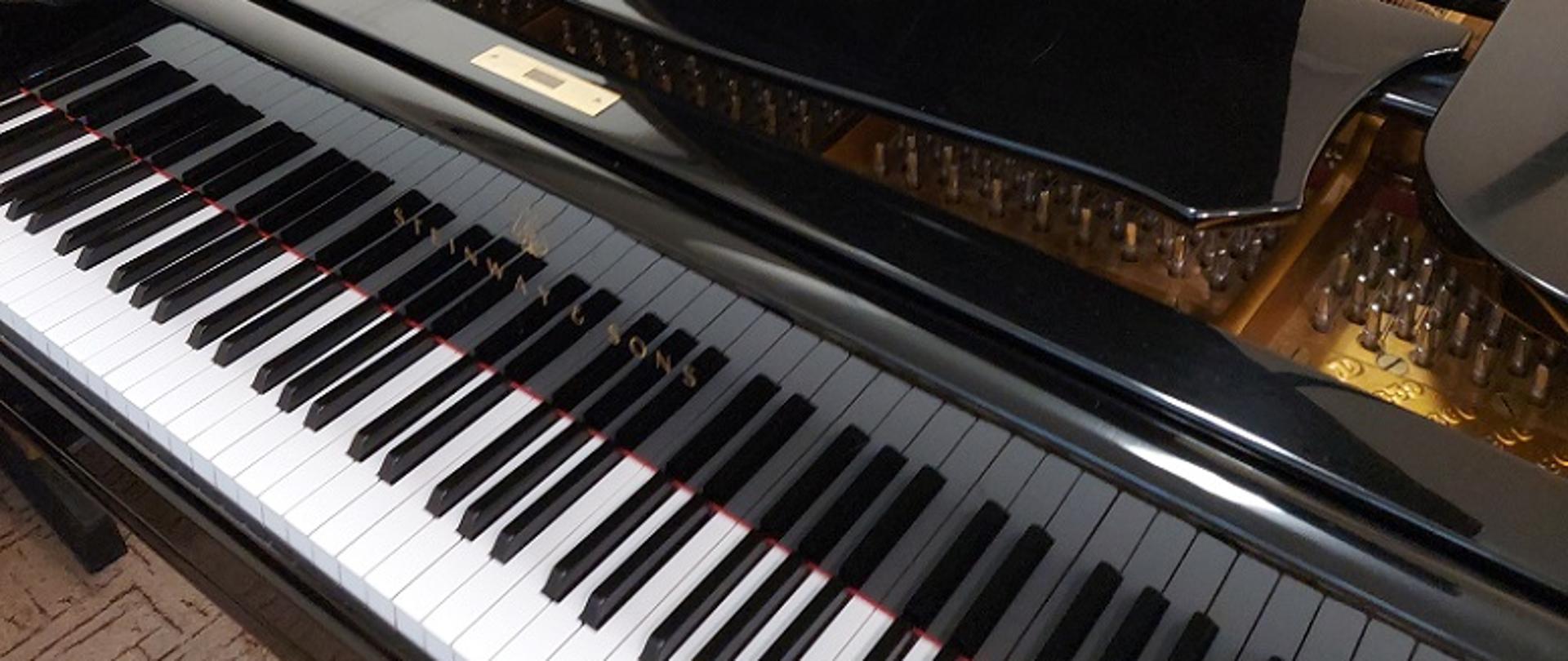 Zdjęcie przedstawia otwarty fortepian oraz czarno-białą klawiaturę