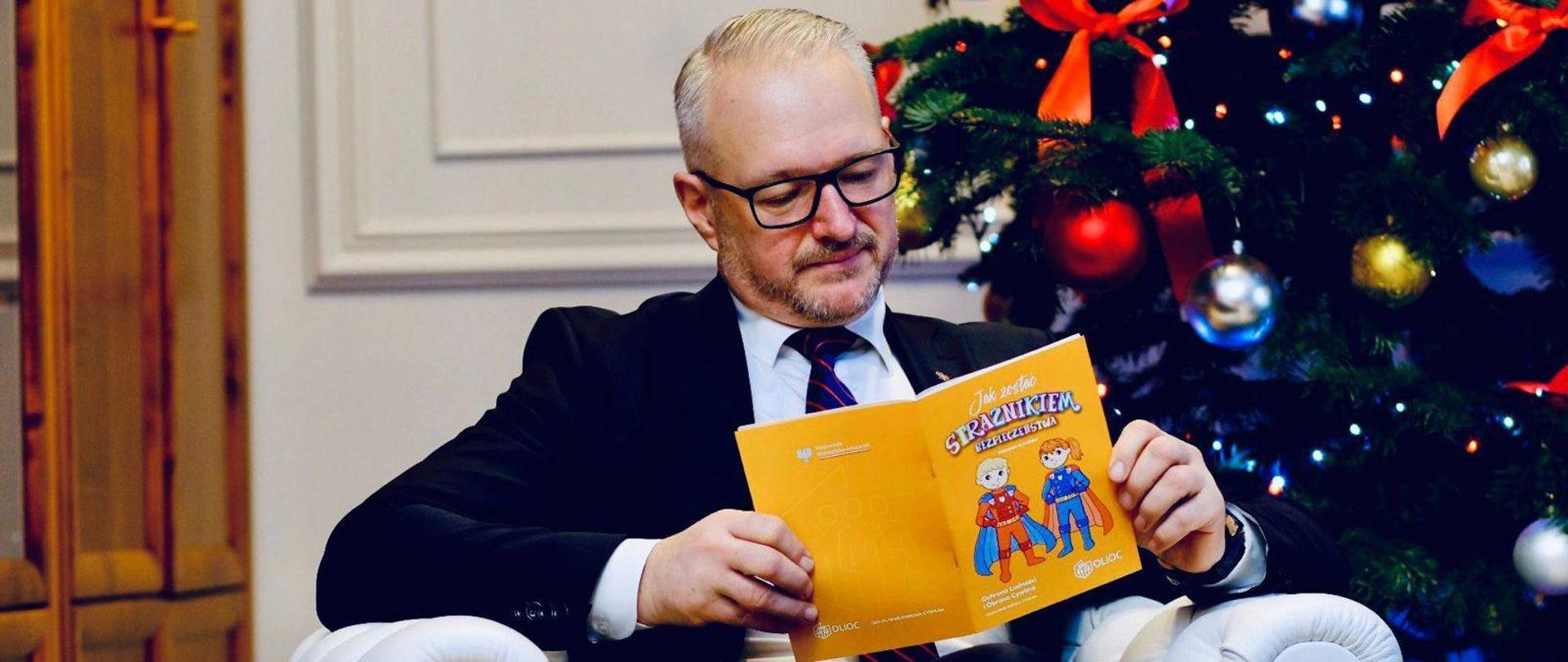 Mężczyzna siedzi na fotelu i czyta książkę 