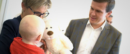 Minister Witold Bańka daje dziecku pluszowego misia