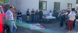 Zdjęcie przedstawia strażaka instruującego pracowników firmy na temat udzielania pierwszej pomocy