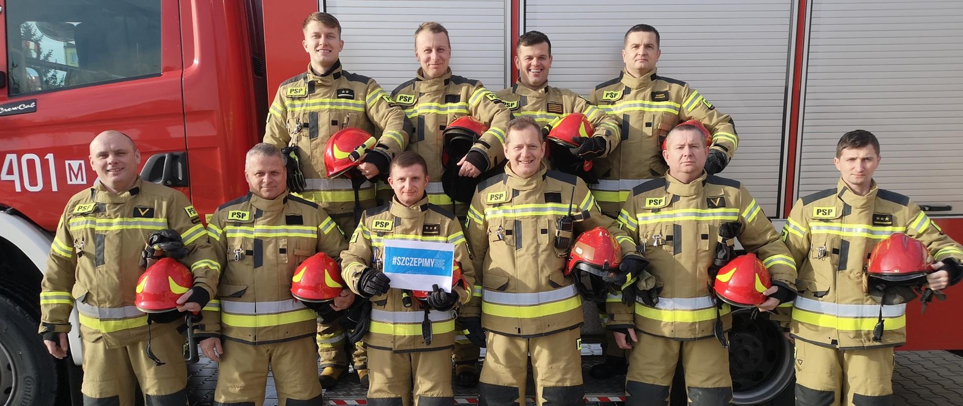 Na zdjęciu dziesięciu strażaków, w tle samochód strażacki.