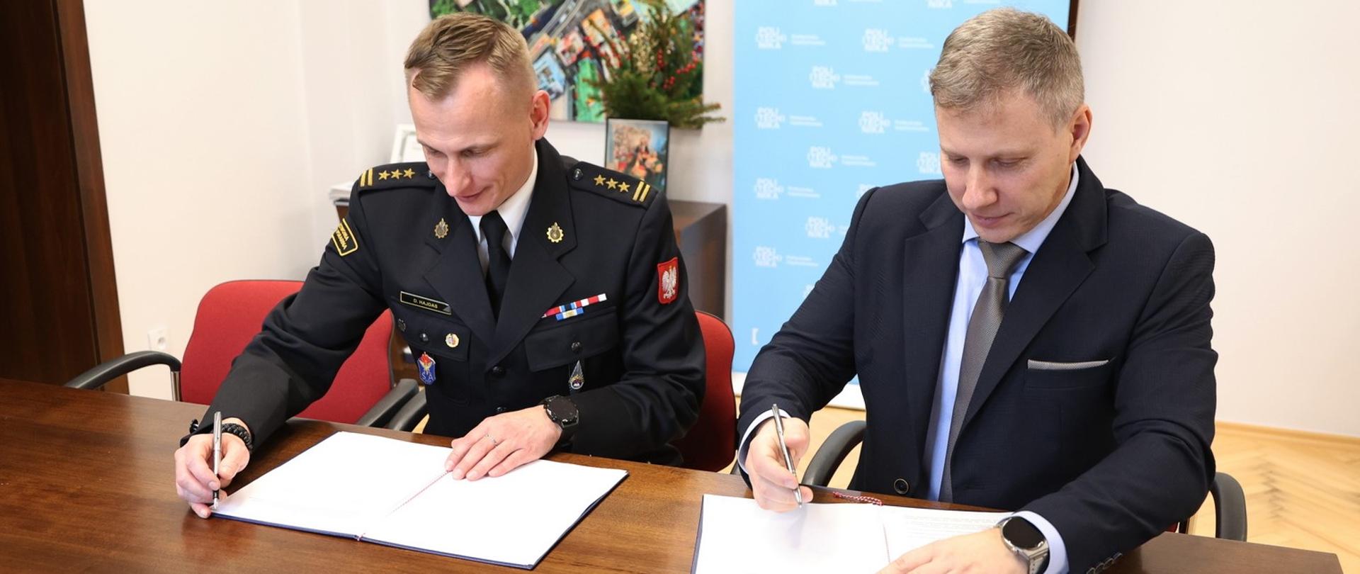 Za stołem konferencyjnym siedzą od lewej Zastępca Komendanta Centralnej Szkoły PSP oraz prorektor do spraw rozwoju Politechniki Częstochowskiej. Obaj panowie podpisują leżące przed nimi porozumienie