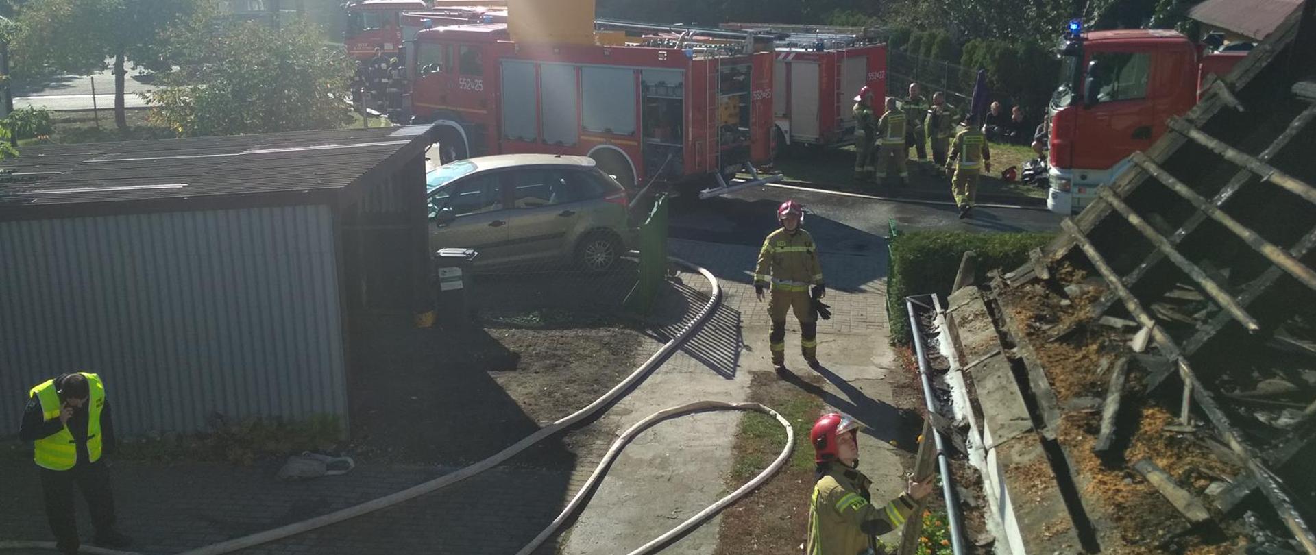 Na zdjęciu pora dzienna, słonecznie. Widać trzy wozu PSP oraz strażaków po zakończonych działaniach.