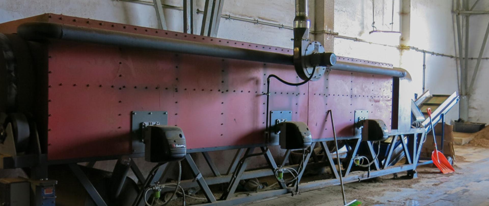 Wnętrze hali magazynowej, w tle urządzenia maszyny wykorzystywane do produkcji nielegalnych wyrobów tytoniowych.