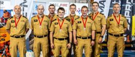 Strażacy w piaskowych mundurach odbierają medale za zajęcie drugiego miejsca w zawodach