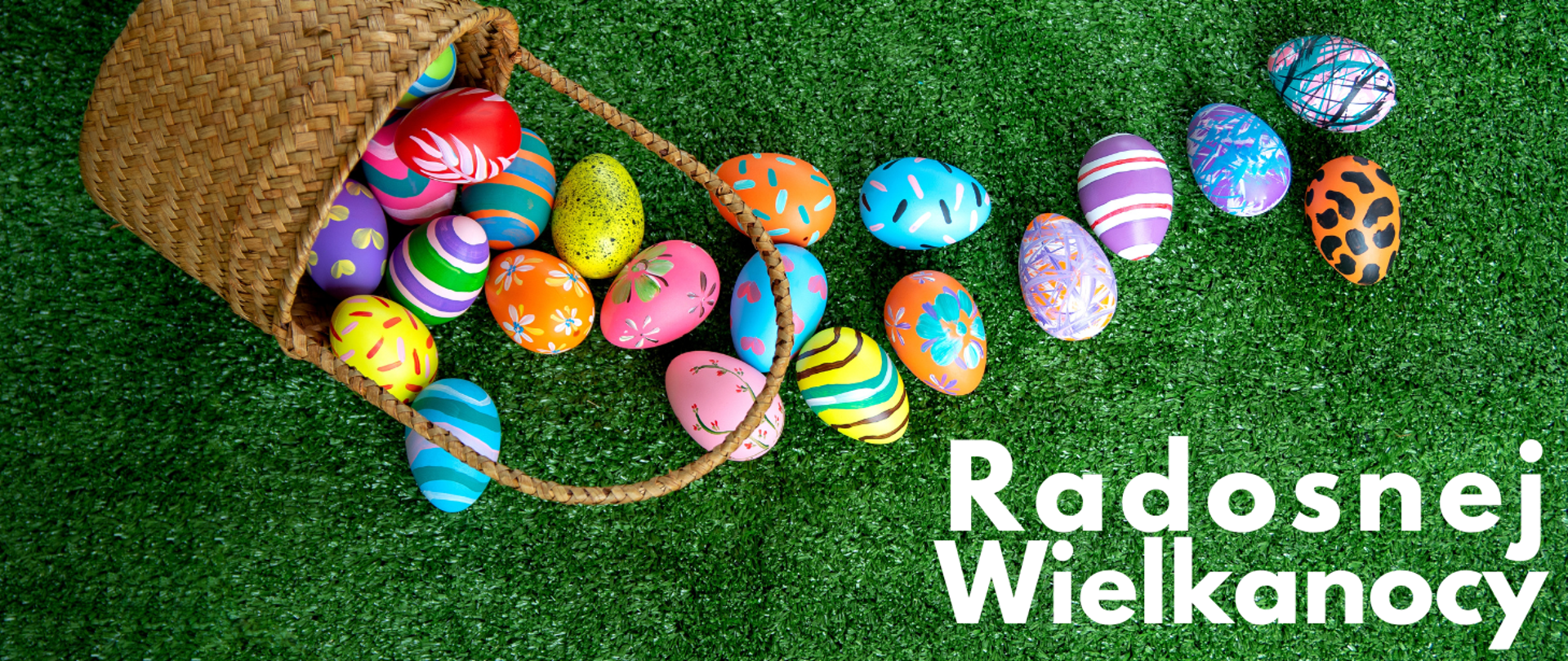 Tło obrazka to trawa w kolorze zielonej trawy. U góry obrazka po lewej stronie znajduje się koszyk wiklinowy, z którego wysypały się kolorowe pisanki. Po prawej stronie u dołu obrazka biały napis: "Radosnej Wielkanocy".
