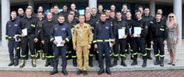 Grupowe zdjęcie uczestników szkolenia (26 osób) w towarzystwie Zastępcy Komendanta Centralnej Szkoły PSP oraz pracowników Szkoły (kobieta oraz 4 funkcjonariuszy) nadzorujących szkolenie