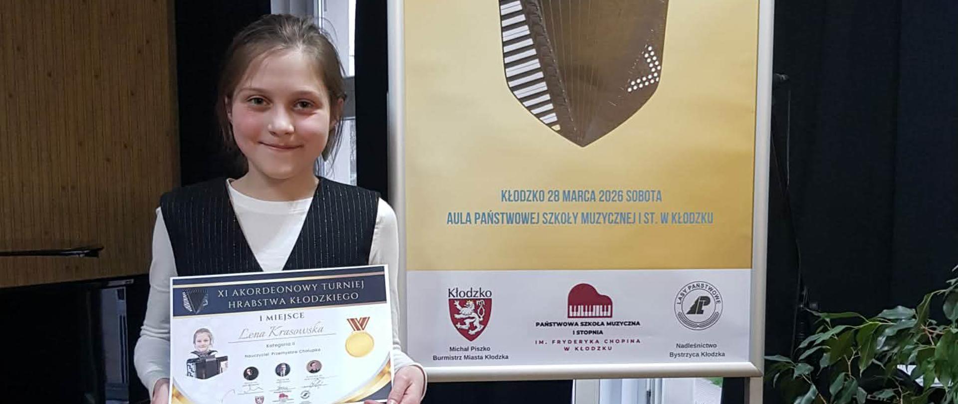 Uczennica z dyplomem konkursowym, z prawej strony baner XI Turnieju Hrabstwa Kłodzkiego.