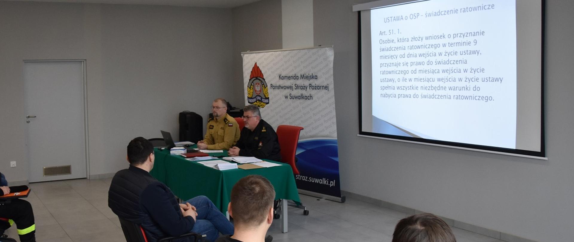 Zdjęcie obrazuje strażaków PSP i OSP w tle baner KM PSP w Suwałkach i slaid z zapisami Ustawy o OSP 