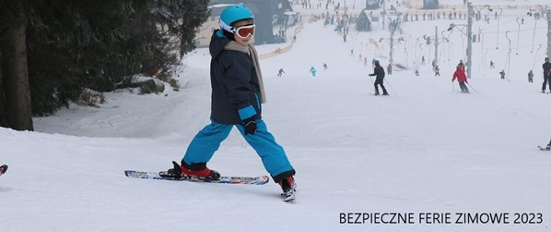 Stok narciarski, dziecko w kasku i nartach na stoku