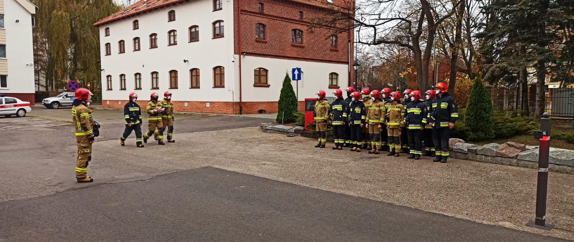Zdjęcie ukazuje funkcjonariuszy z Jednostki Ratowniczo - Gaśniczej nr 1 w Olsztynie w trakcie uroczystego podniesienia flagi państwowej na maszt z okazji rocznicy obchodów Narodowego Święta Niepodległości