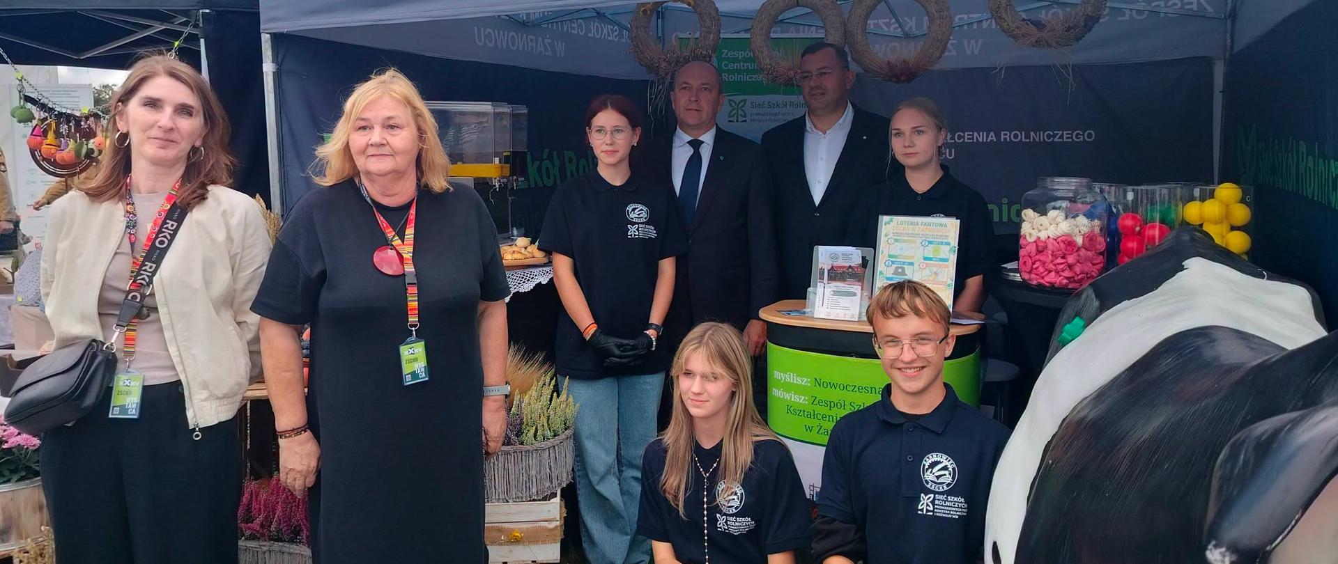 grupa osób pozuje do zdjęcia, w tle banery, przekąski ulotki