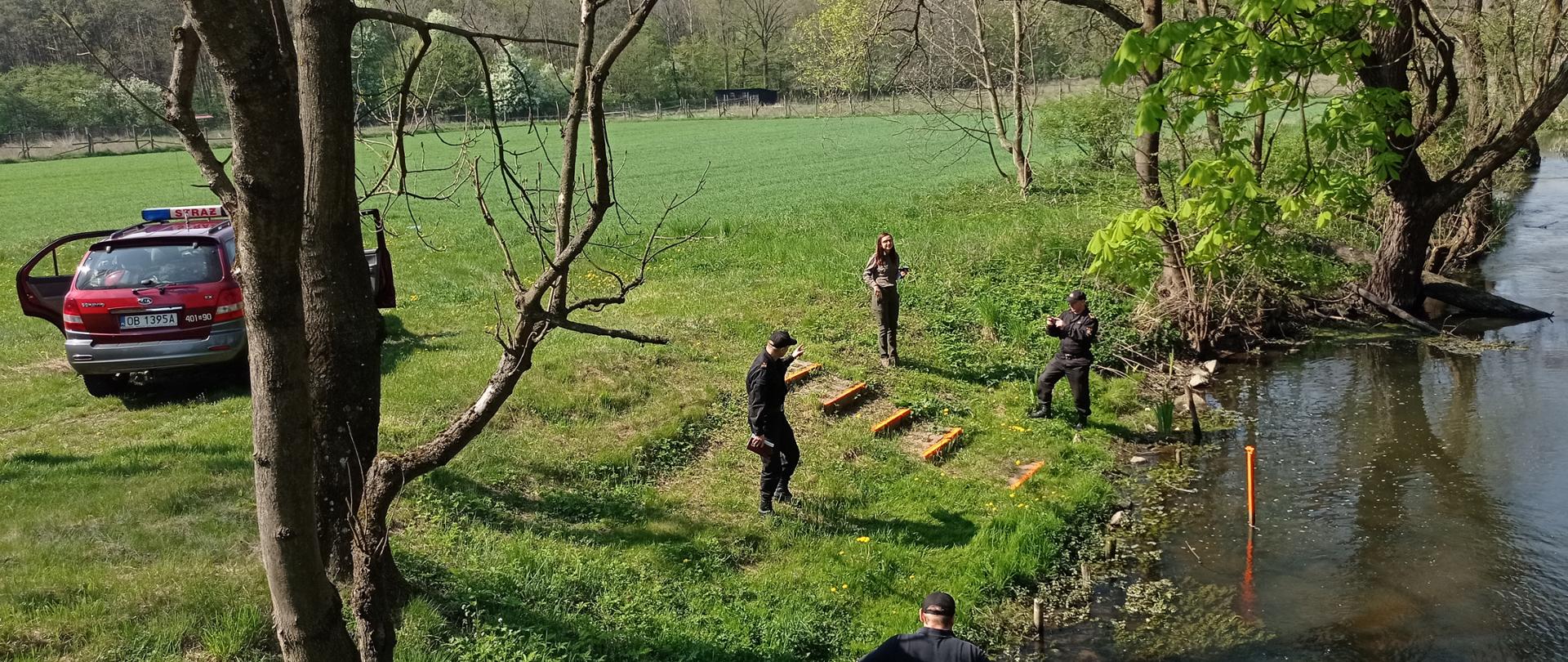 Kontrola terenów leśnych Nadleśnictwa Brzeg - zdjęcie przedstawia samochód operacyjny oraz funkcjonariuszy PSP w tle zbiornik wodny