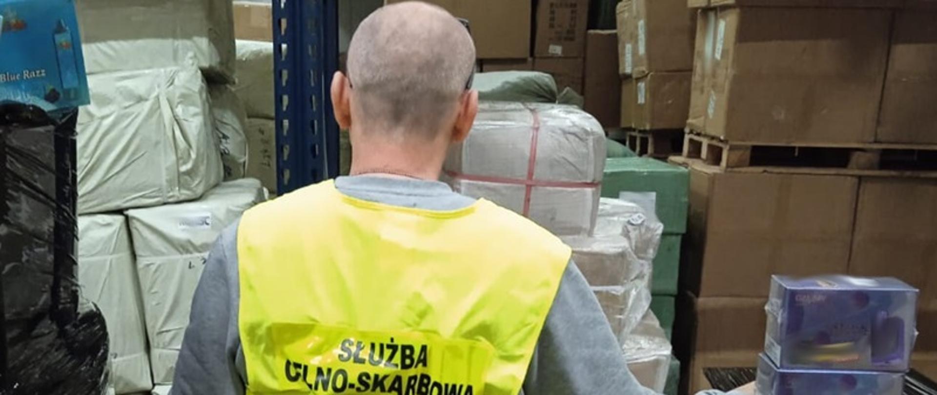 Funkcjonariusz stoi przed pudełkami z e-papierosami.