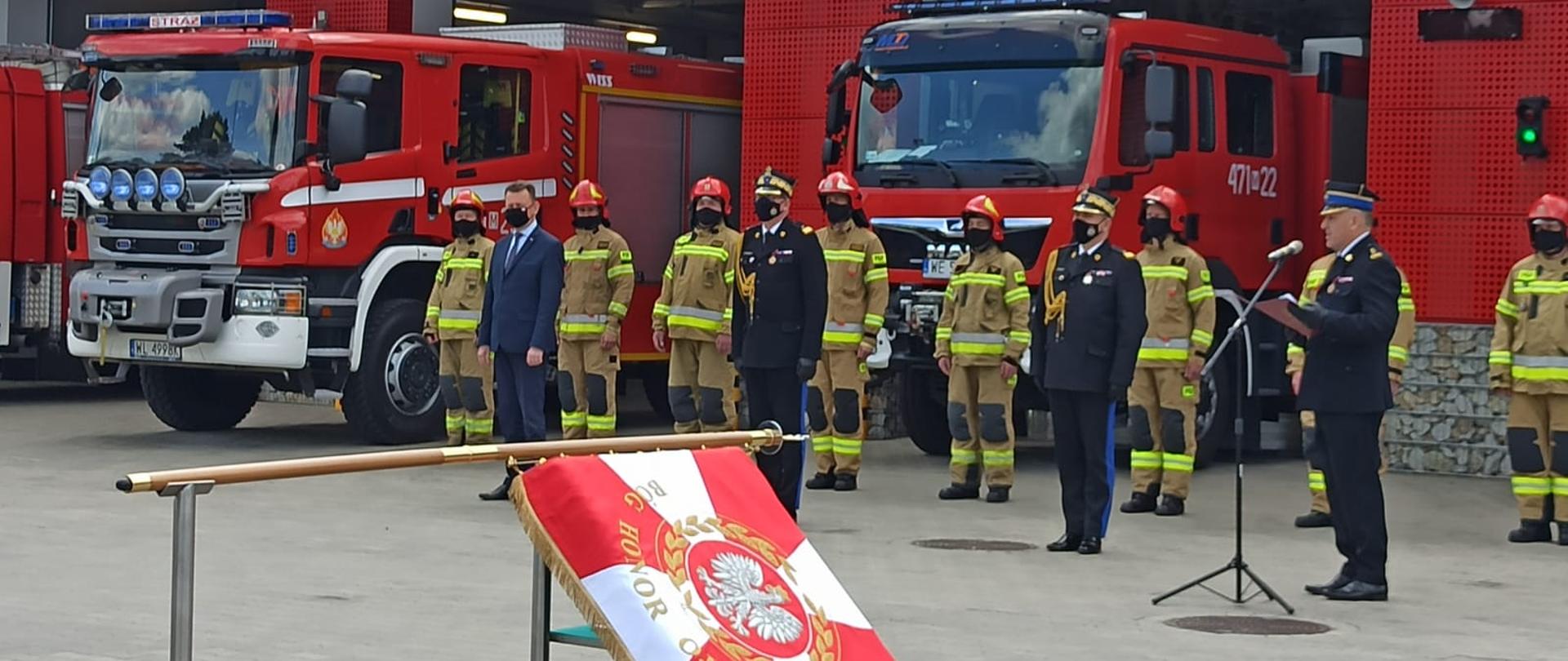 Uroczystość nadania sztandaru. Goście honorowi uroczystości na tle samochodów pożarniczych