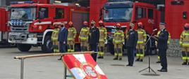 Uroczystość nadania sztandaru. Goście honorowi uroczystości na tle samochodów pożarniczych