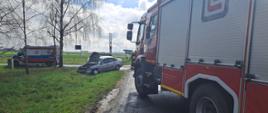 Zdjęcie przedstawia wóz strażacki, karetkę pogotowia ratunkowego oraz pojazd po kolizji drogowej.