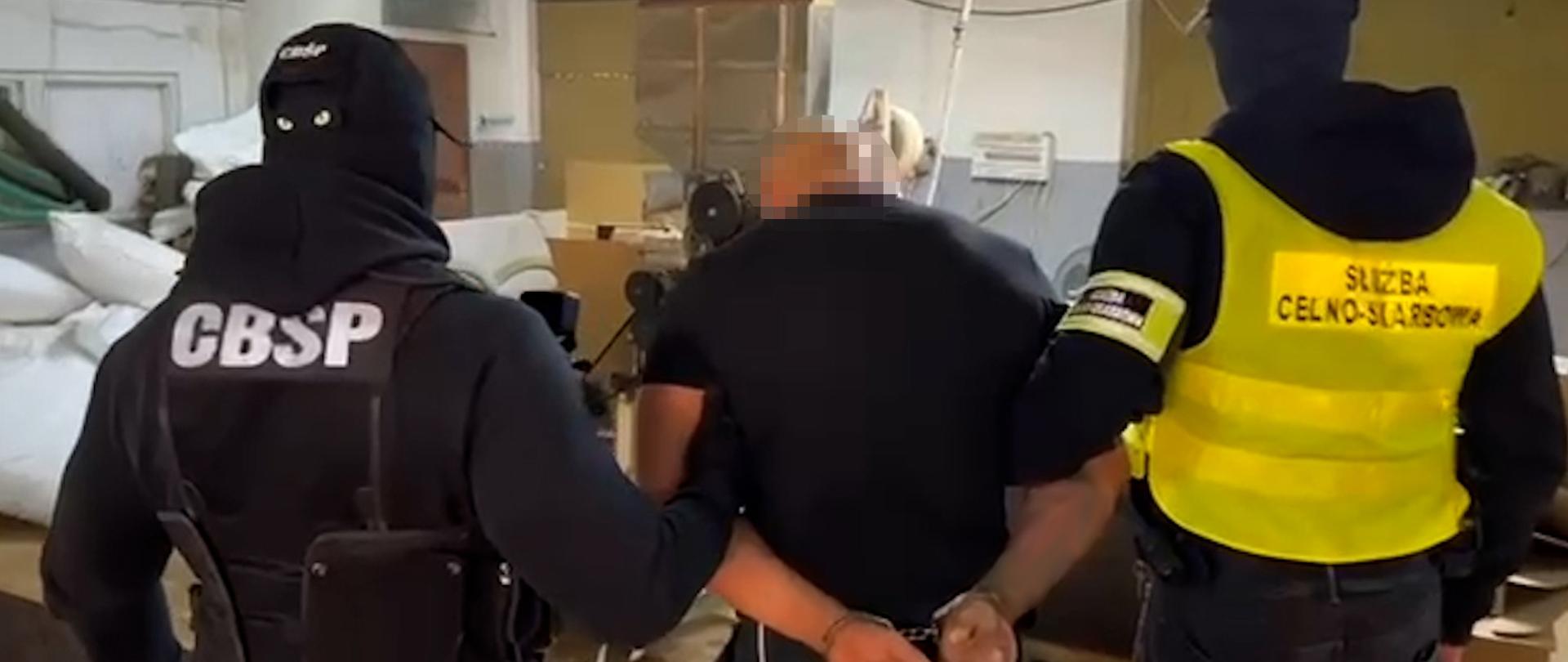 Funkcjonariusze Służby Celno-Skarbowej i Centralnego Biura Śledczego z zatrzymanym mężczyzną.