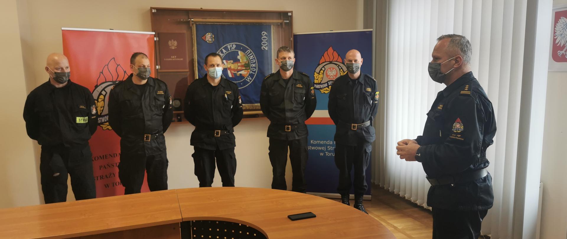 Kujawsko-Pomorski Komendant Wojewódzki PSP st. bryg. Robert Wiśniewski przemawia do dotychczasowych Dowódców i Zastępców Grup Specjalistycznych wchodzących w skład Centralnego Obwodu Operacyjnego. Dziękuje im za dotychczasową współpracę. Naprzeciwko ustawieni w rzędzie są od prawej strony: mł. kpt. Sławomir Grudziński, st. kpt. Łukasz Wróblewski, bryg. Arkadiusz Stec, mł. bryg. Wojciech Laurentowski i mł. kpt. Arkadiusz Szewczyk. W tle na ścianie umieszczony jest sztandar Komendy Miejskiej PSP w Toruniu. 