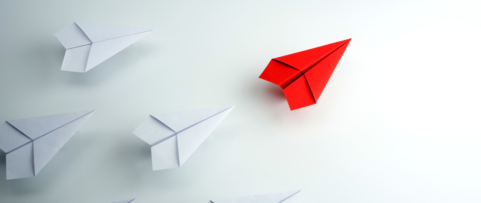 Papierowe białe samolotu, z przodu - jeden czerwony, symbolizujący lidera.
