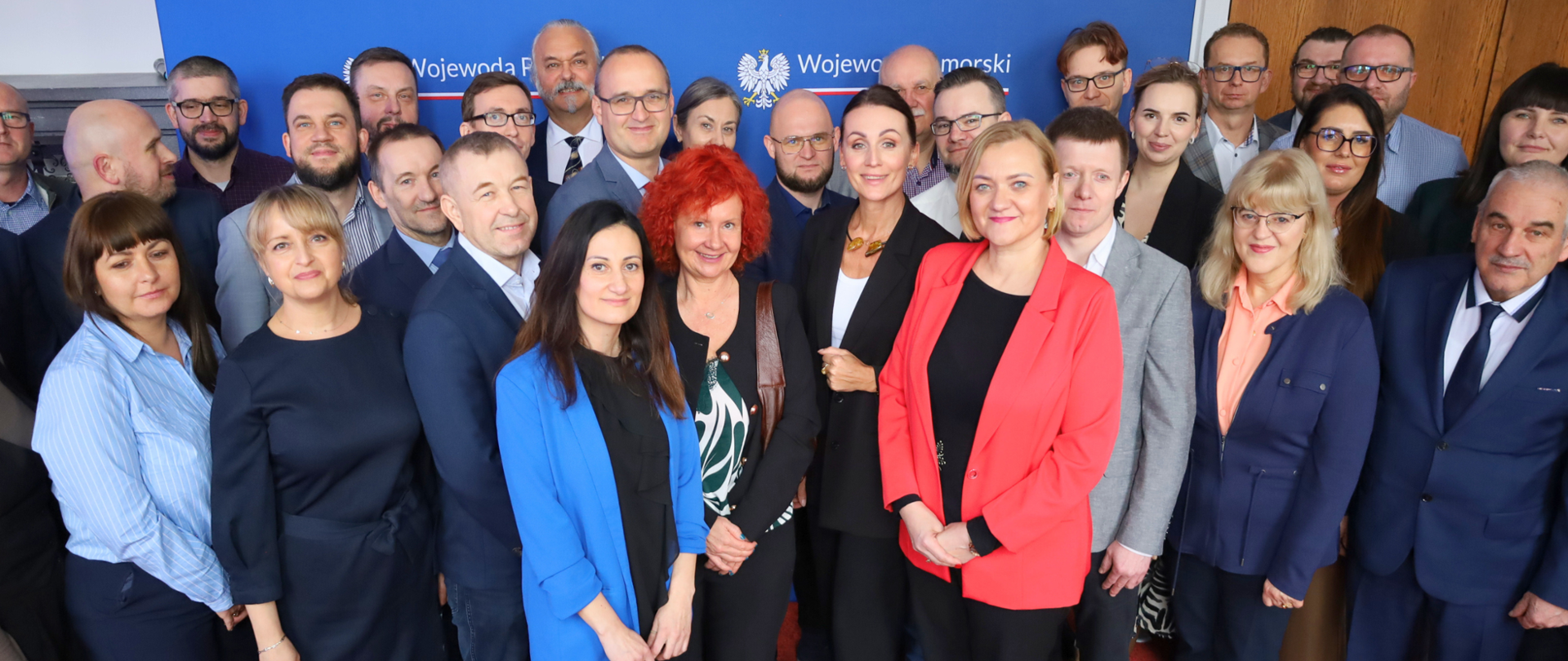 grupa osób pozuje do zdjęcia, w tle baner z napisem wojewoda pomorski
