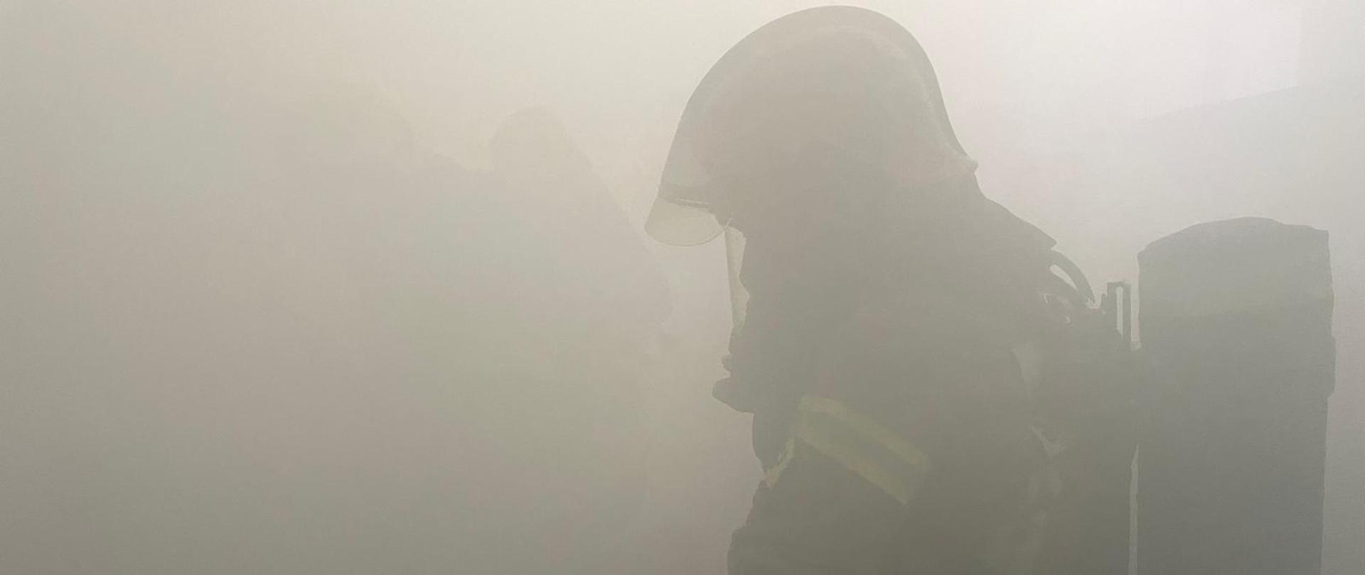 Zdjęcie przedstawia strażaka w zadymionym pomieszczeniu